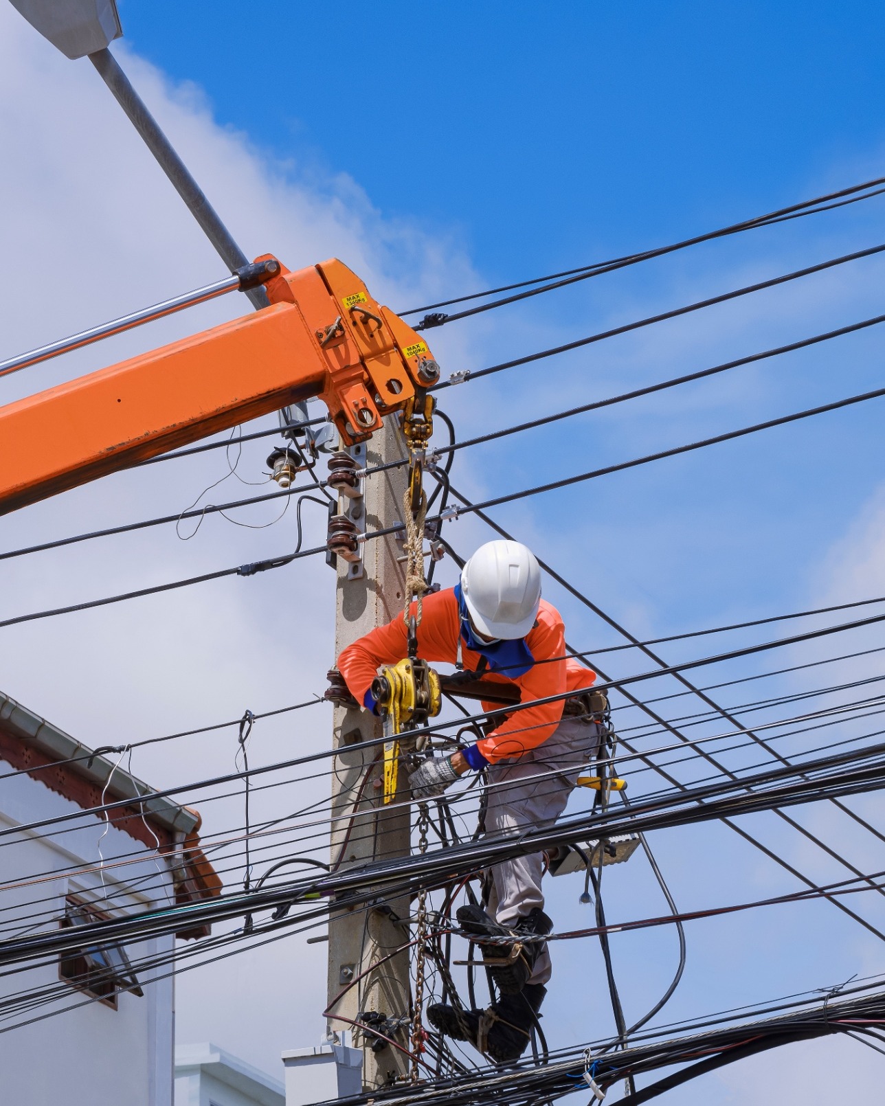 Electrical technician installing power lines with a crane truck