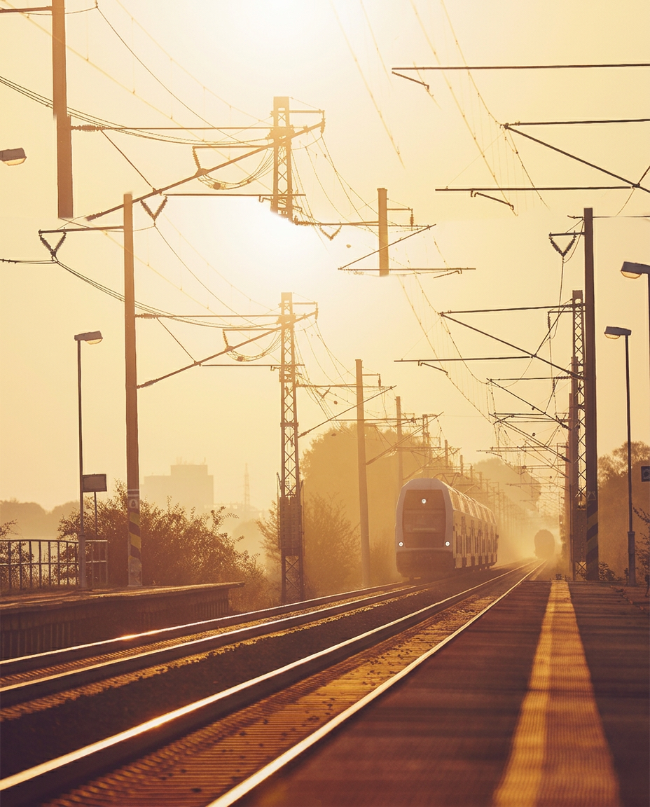 Passenger train on electrified rail tracks at sunrise